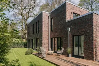 weigeschossiges Klinkerhaus in Hamburg mit schmalen Obergeschossfenstern, großen Gartenfenstern und rotbunter rustikaler Klinkerfassade in Sortierung 68 DF.