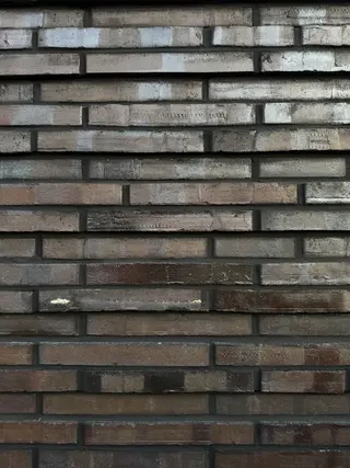 Nahaufnahme der strukturierten Oberfläche dunkler Langformat-Klinker einer modernen Fassade